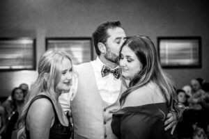 A groom embraces his daughters during a dance in Cambria, CA.