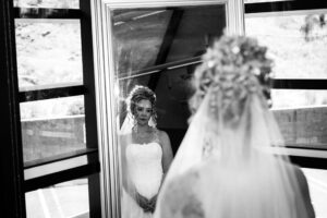 Bride sentimentally looking into mirror before wedding ceremony.