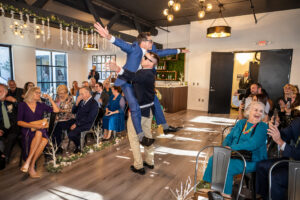 Two groomsmen hold each other up at the start of a wedding ceremony in Long Beach, California.