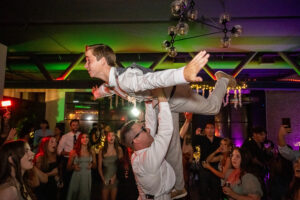 A groomsman holds up another groomsman at a wedding reception in Long Beach, California.